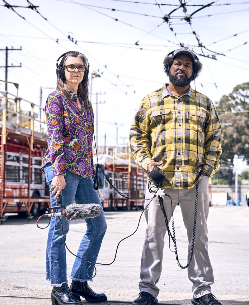 Nigel and Earlonne, hosts of Ear Hustle, stand in a parking lot